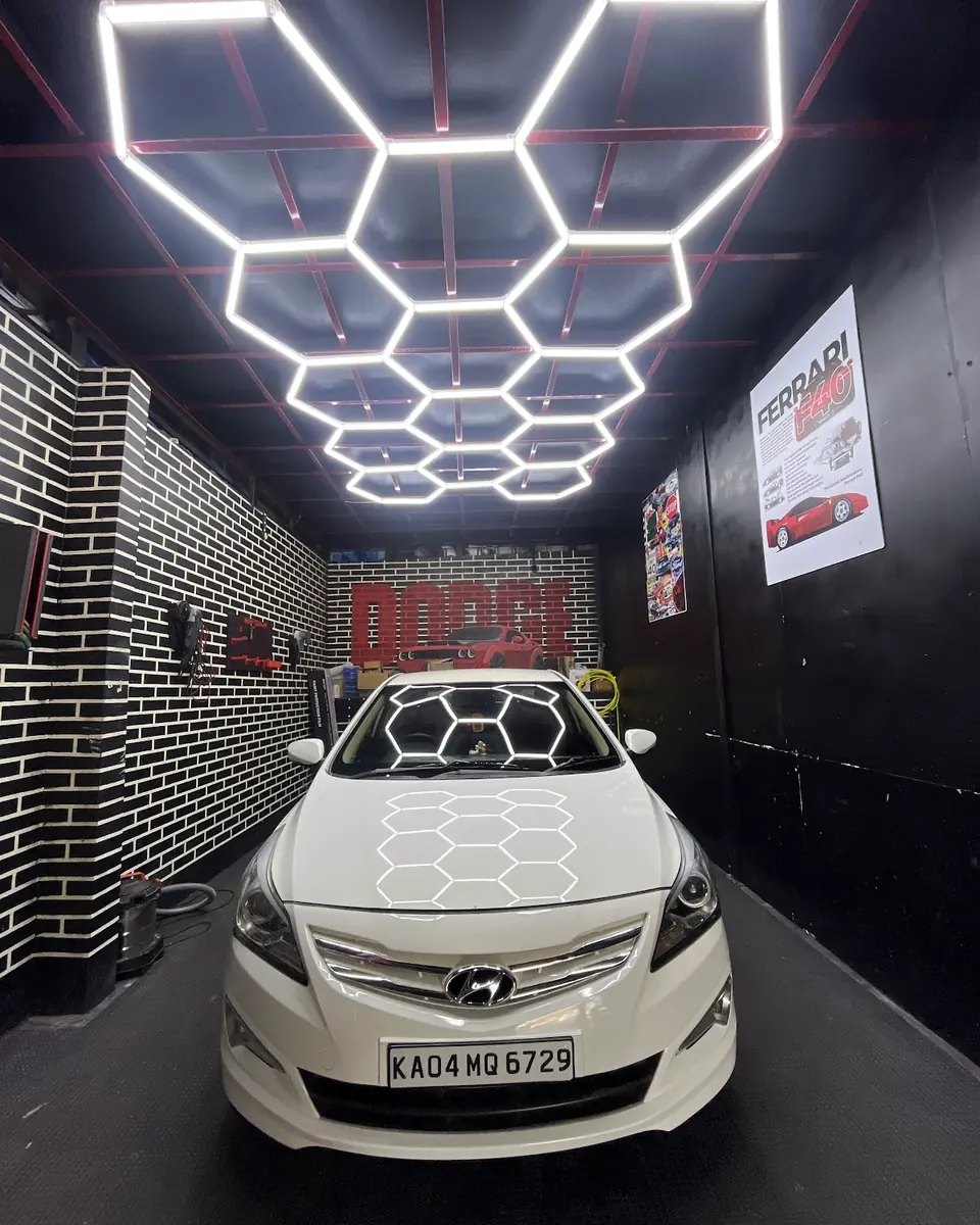 White sedan under hexagonal ceiling lights in the detailing bay